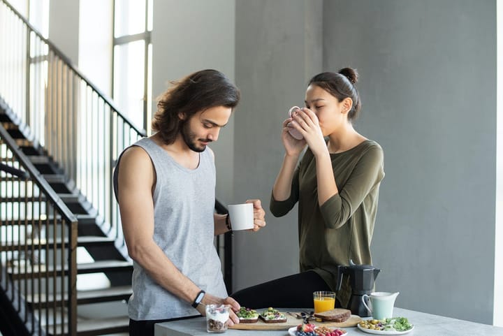 Couple at their breakfast table holding coffe cups