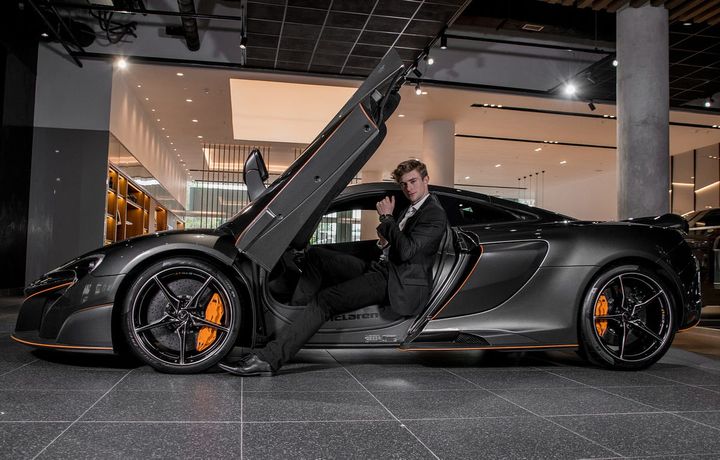Handsome young man with a black and orange supercar