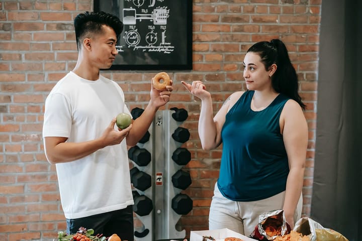 An overweight woman choosing a donut offered by her trainer