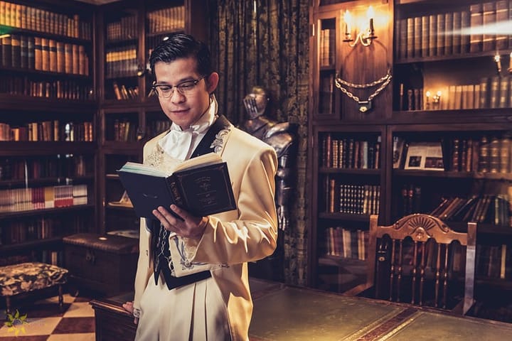 Intelligent looking Asian man reading in a well-lit library