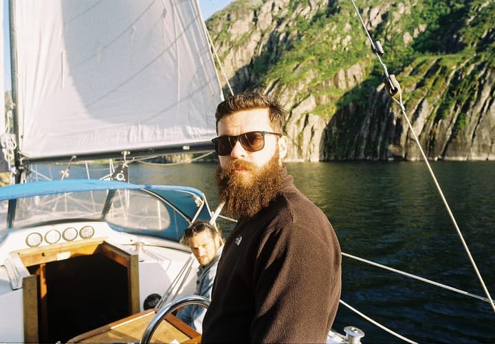 Bearded man wearing shades and standing in a yacht