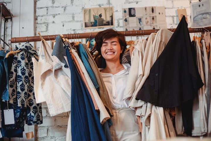 Woman with a happy closed-eyes face amidst hung clothes