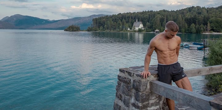 Ripped man standing by a lake