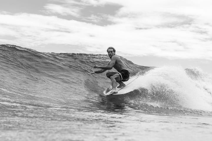 Black and white image of a shirtless muscular surfer