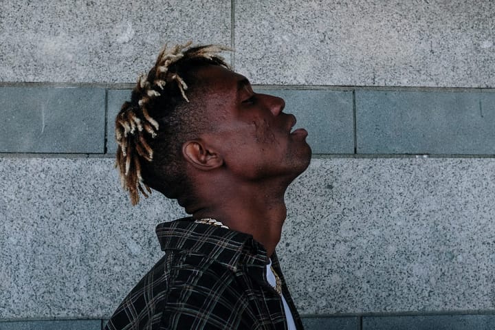 Black man with light brown short hair standing with his head thrown back