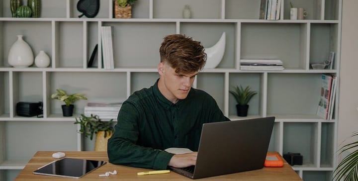 Young man in a green long-sleeve shirt looking at his laptop