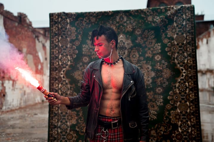 Exotic looking man holding a fire stick in front of a carpet