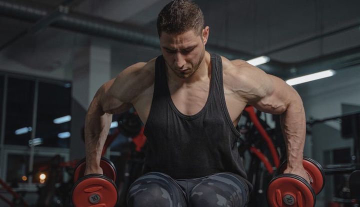 Muscular young man performing shoulder upright raises