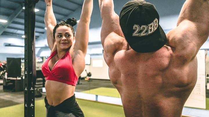 Man and woman hanging from a pullup bar